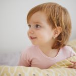 Portrait of Caucasian toddler girl child with redhead smiling and looking away